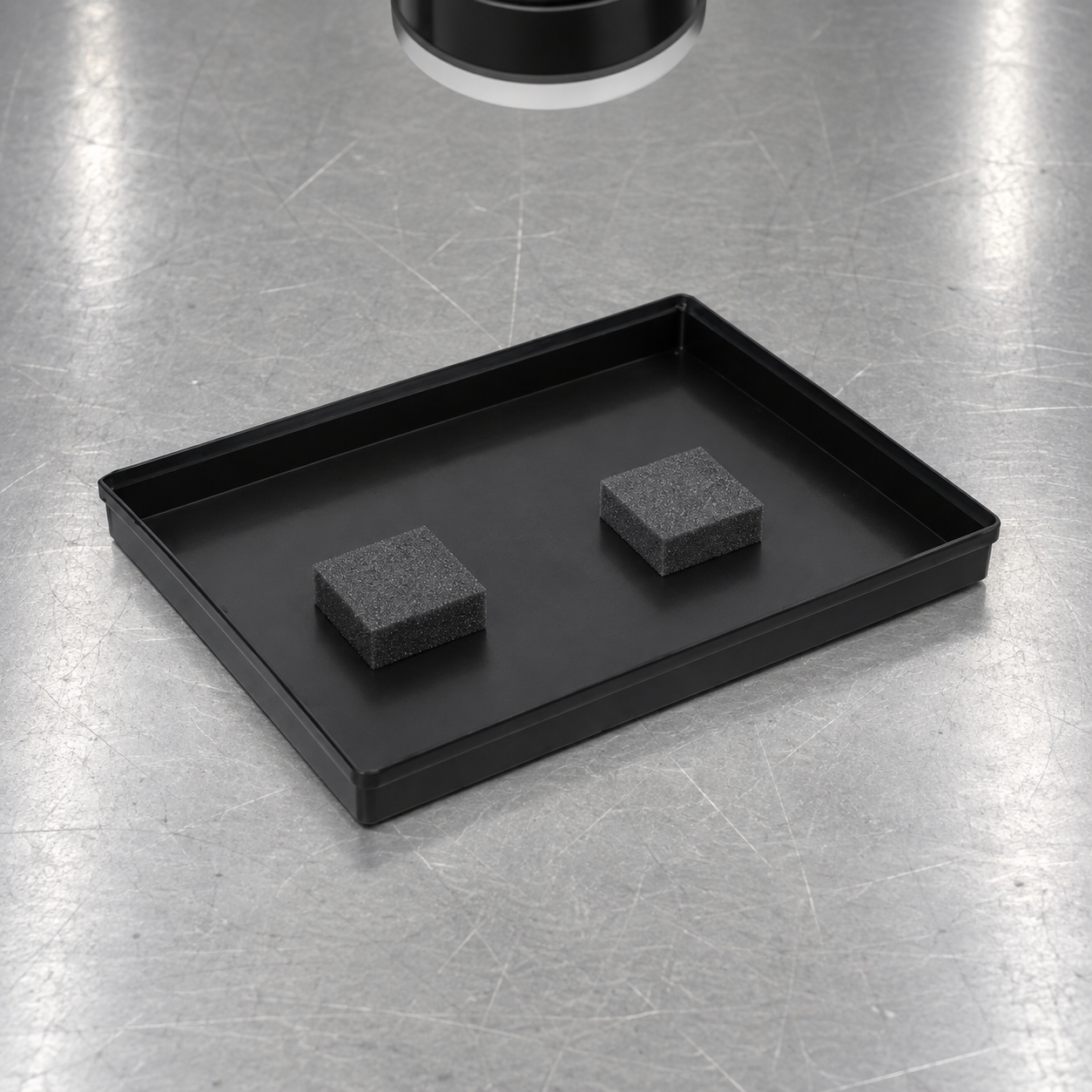 Black shallow ESD tray with neutral test blocks under an overhead camera