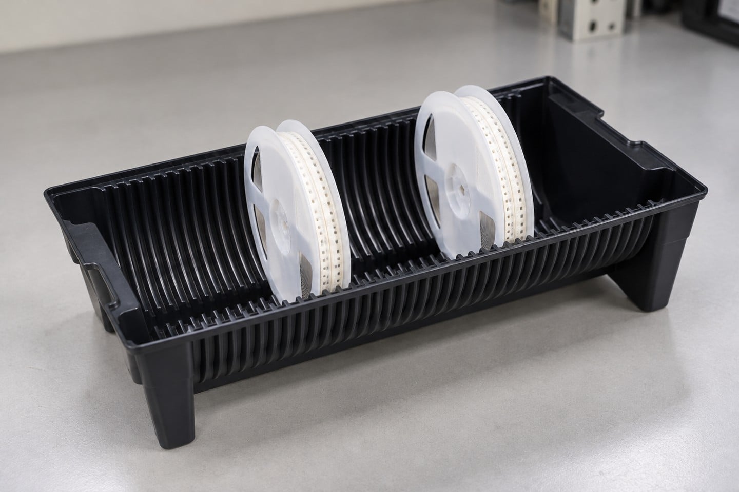 Two white reels seated in separate grooves of a black carrier